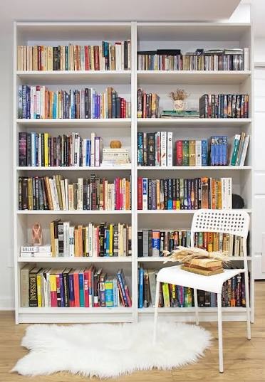A pair of white bookshelves with books and a rug